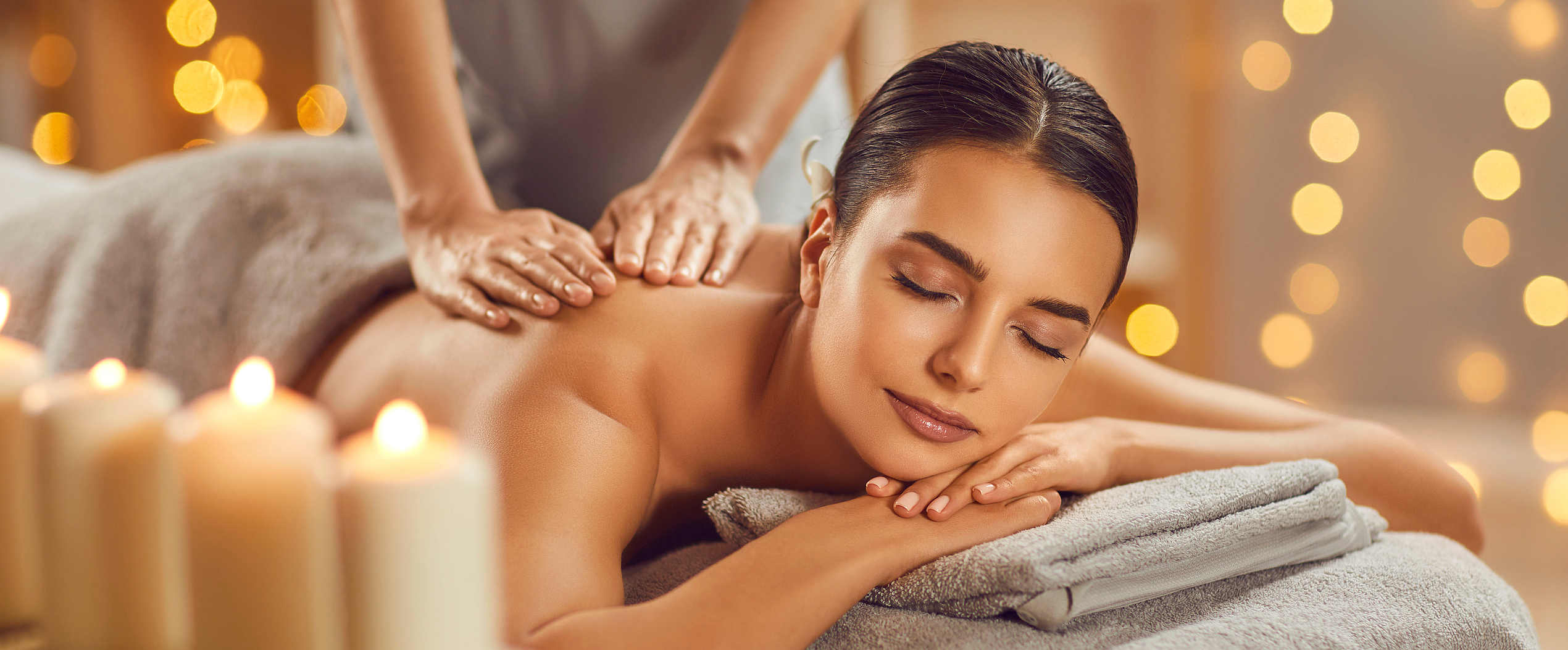 Beautiful young woman enjoying massage in spa salon