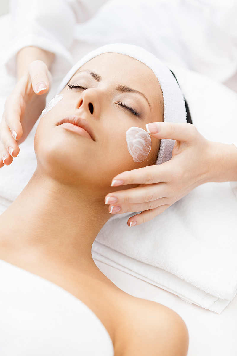 Hands of therapist apply cream to face of woman. Concept of care and youth