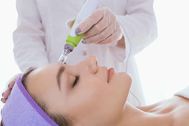 Fractional mesotherapy.A young beautiful woman in the cosmetologist’s office receives fractional mesotherapy for her face. Facial skin rejuvenation. Acne treatment. Hardware cosmetology. Beautician.